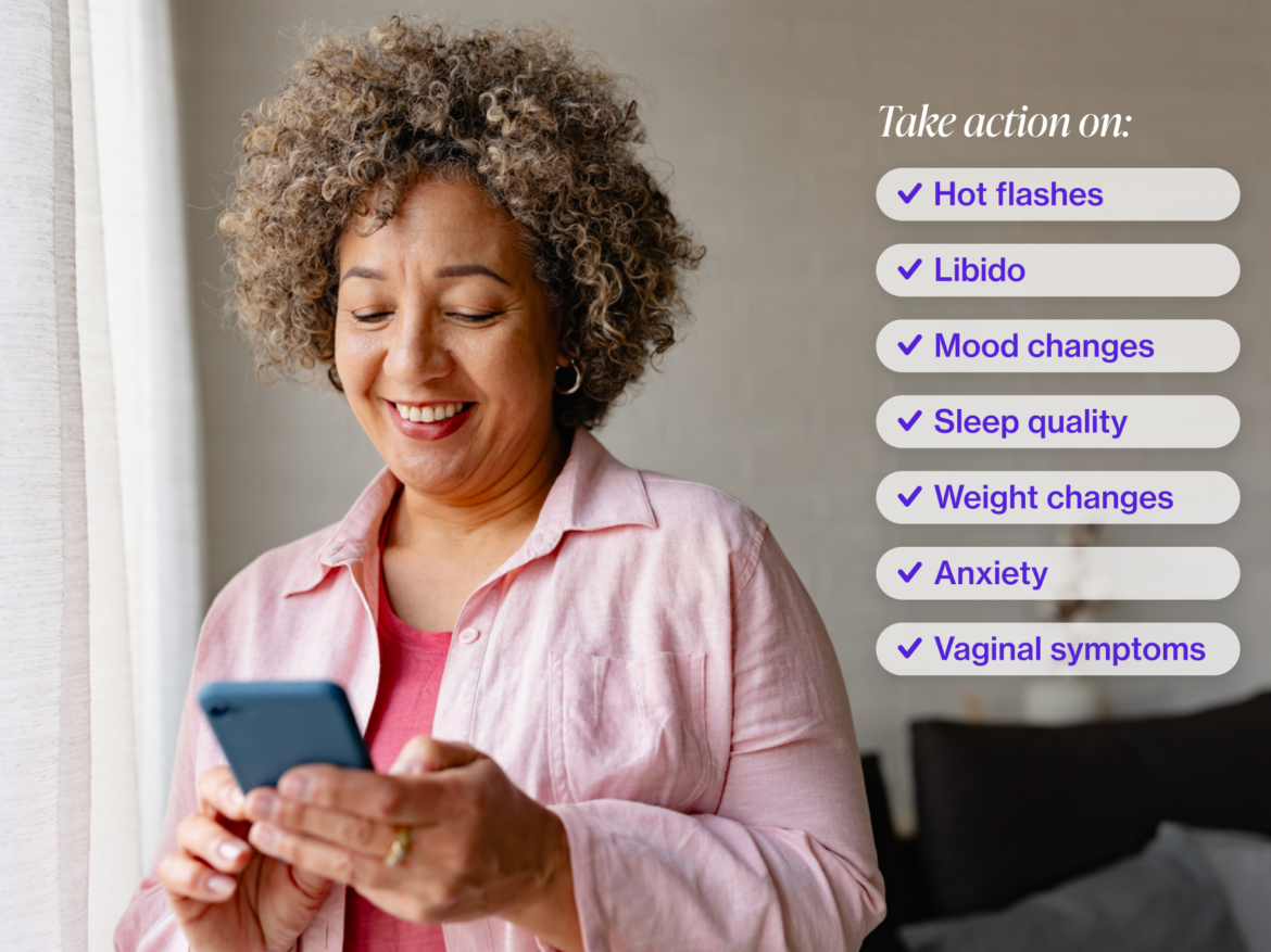 Woman with short curly hair looking at her iphone and smiling