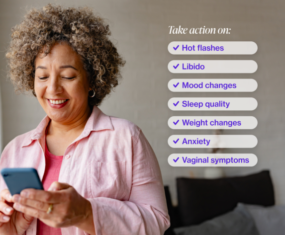 Woman with short curly hair looking at her iphone and smiling