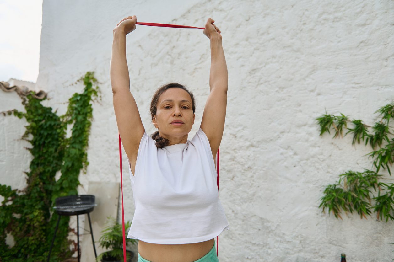 Woman doing overhead press exercise with resistance band